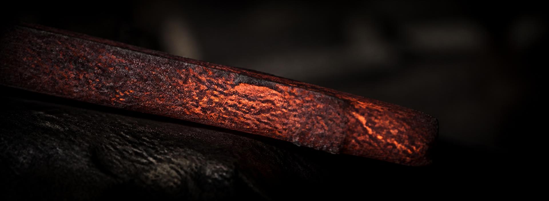 Glowing forged steel bar cooling on an anvil